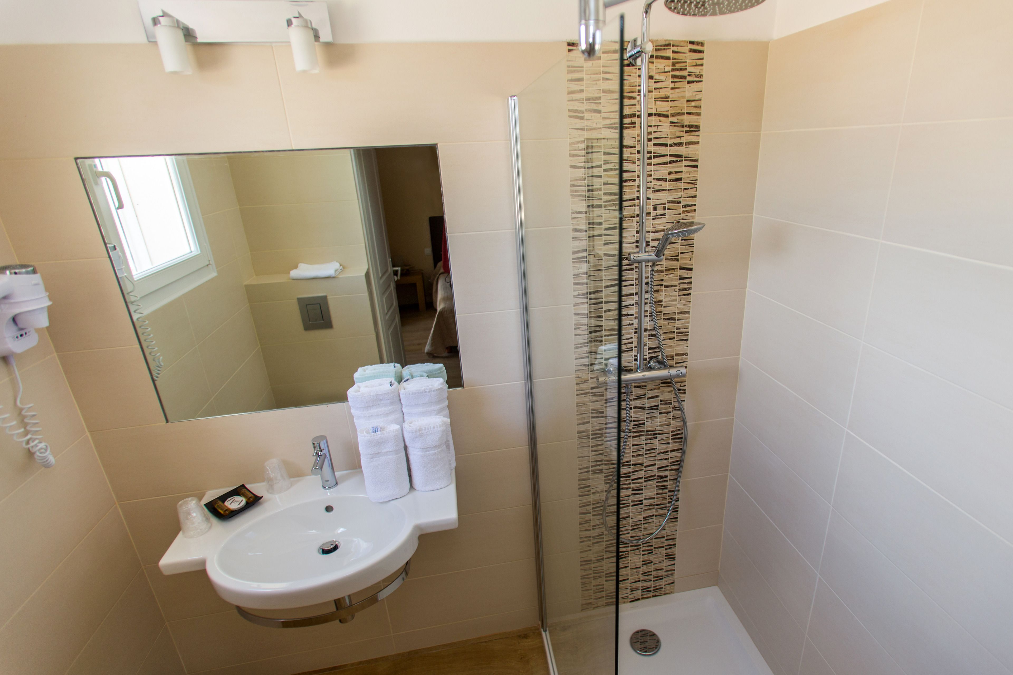 A bathroom with a sink, mirror, and shower.