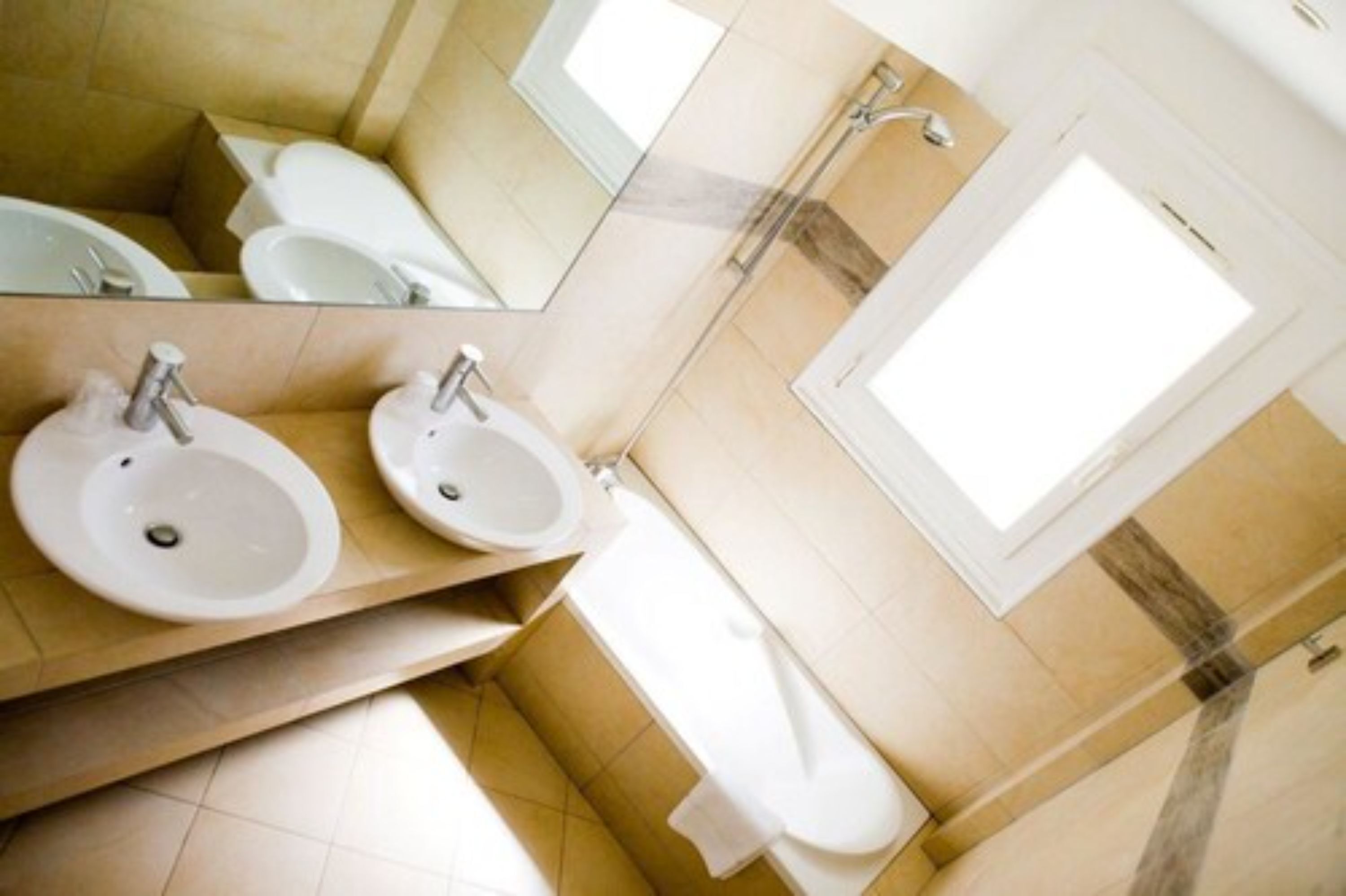 A modern bathroom with two sinks, a toilet, and a shower.