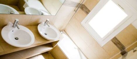 A modern bathroom with two sinks, a toilet, and a shower.