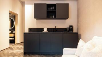 A modern kitchen with dark cabinetry, a built-in coffee machine, and a herringbone-patterned floor.