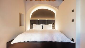 A bedroom with a large bed, an arched ceiling, and a wooden floor.