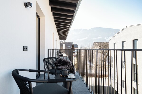 A balcony with a black cat, a table with a teapot and cup, and a view of mountains. - Schwarzer Adler - Concept Living (Vipiteno)
