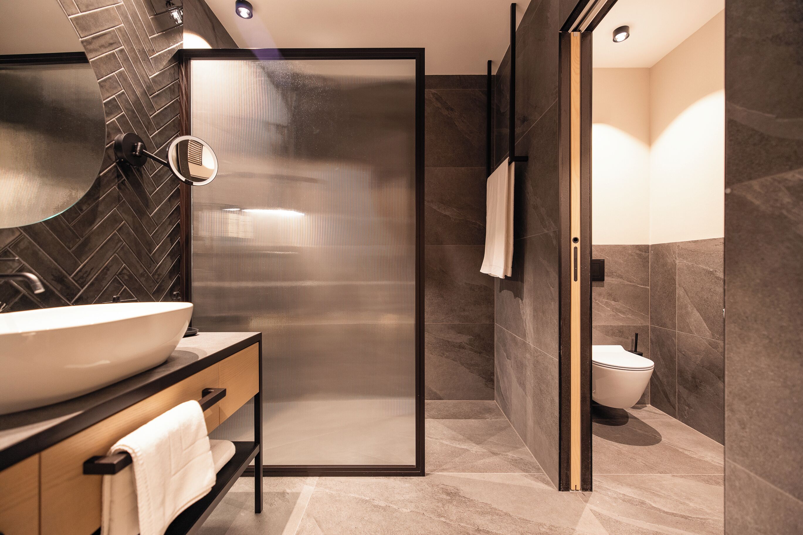 Un baño moderno con un lavamanos grande, una cabina de ducha de vidrio y un inodoro.