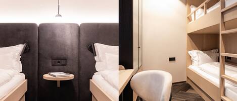 A modern hotel room with two beds, a small table, and a chair.