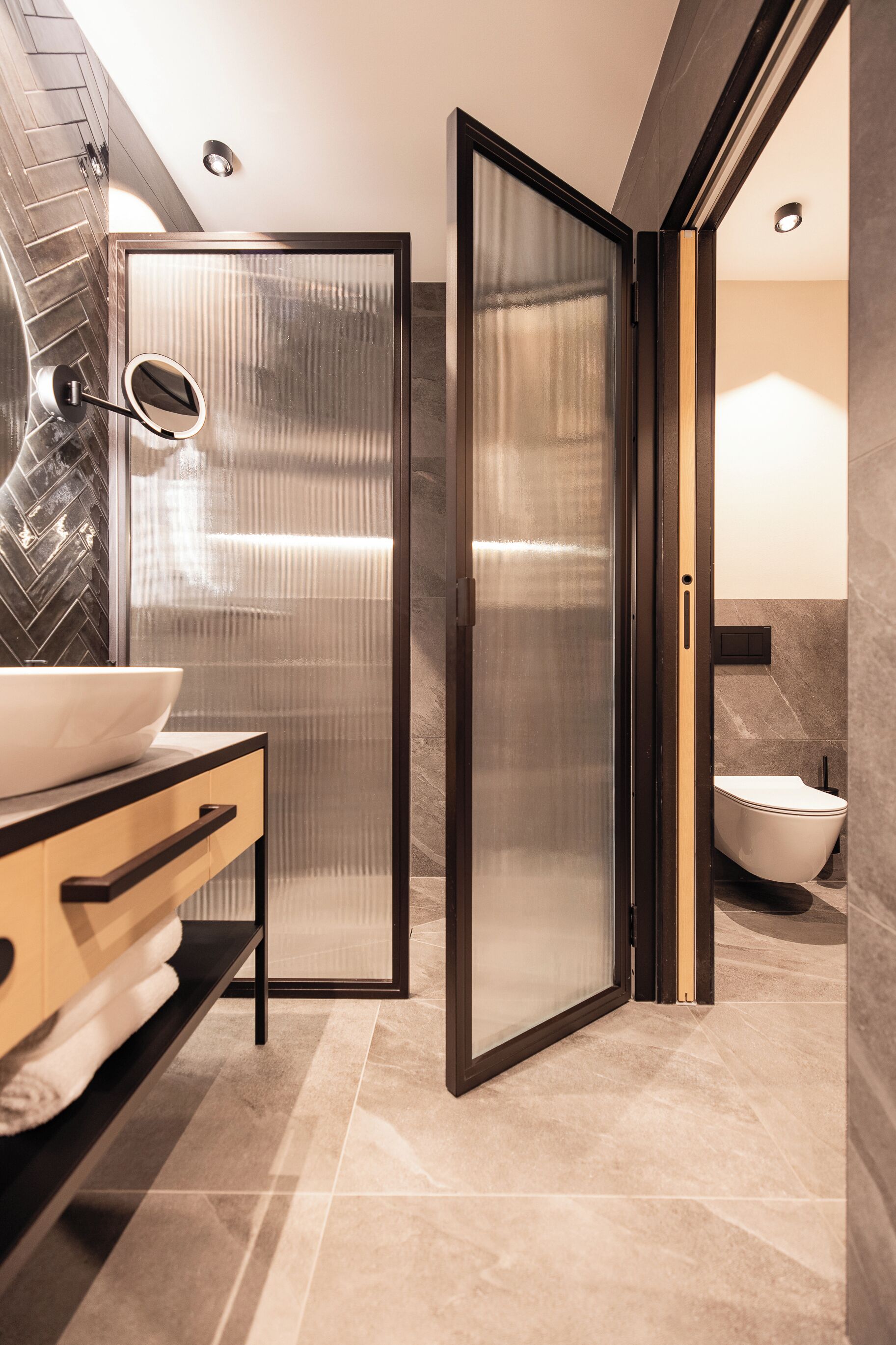 Un baño moderno con cabina de ducha de vidrio, un lavamanos blanco y un inodoro.