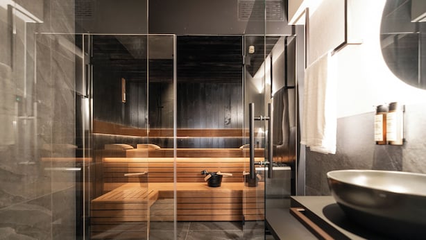 Une salle de bain moderne avec une douche à parois de verre, des bancs en bois, un grand lavabo et un miroir.