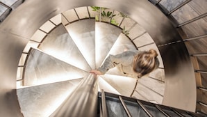 Un escalier en colimaçon avec une main courante, et une personne qui descend.