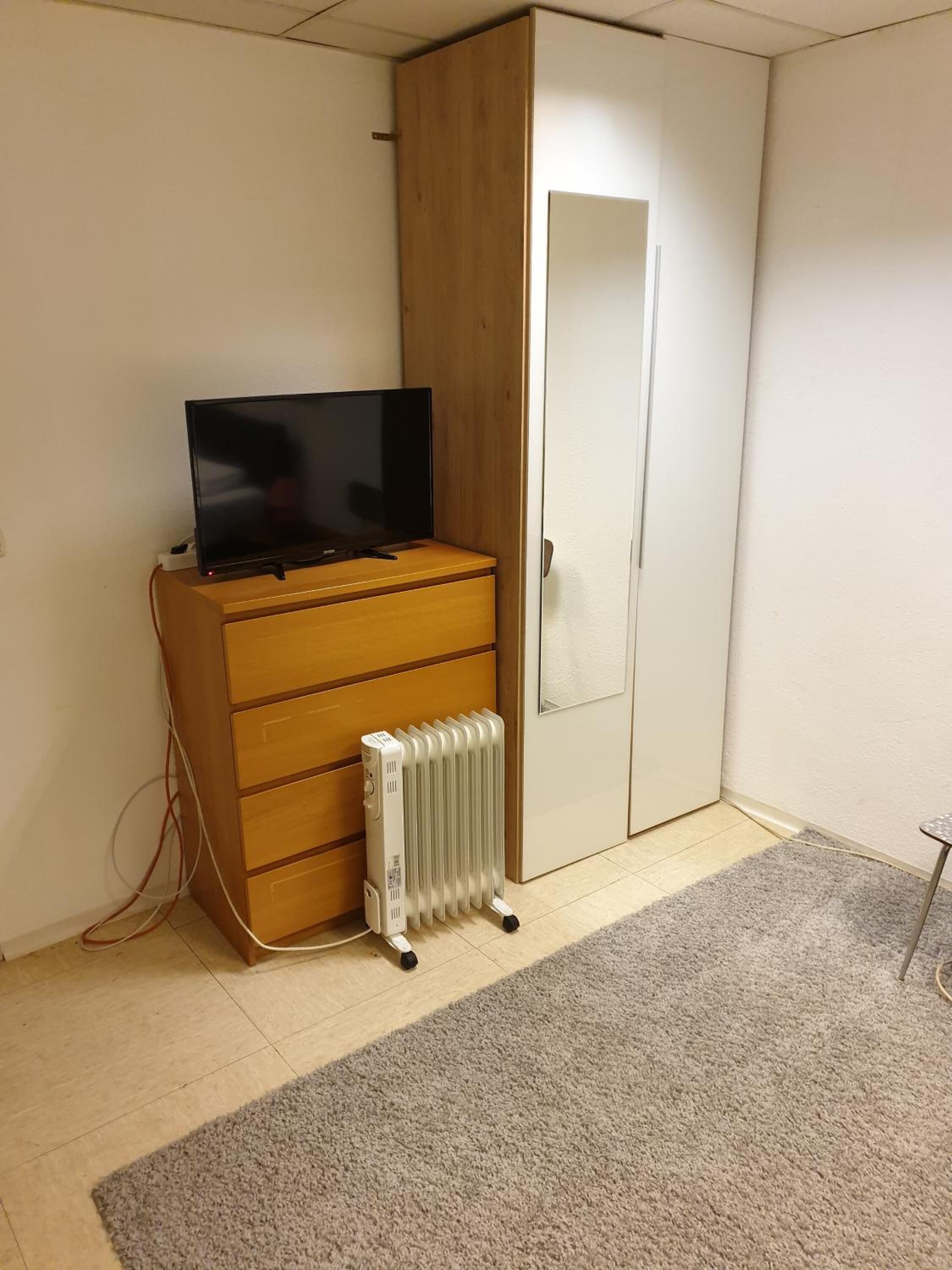 Une pièce avec un meuble en bois, un radiateur blanc et une porte fermée.