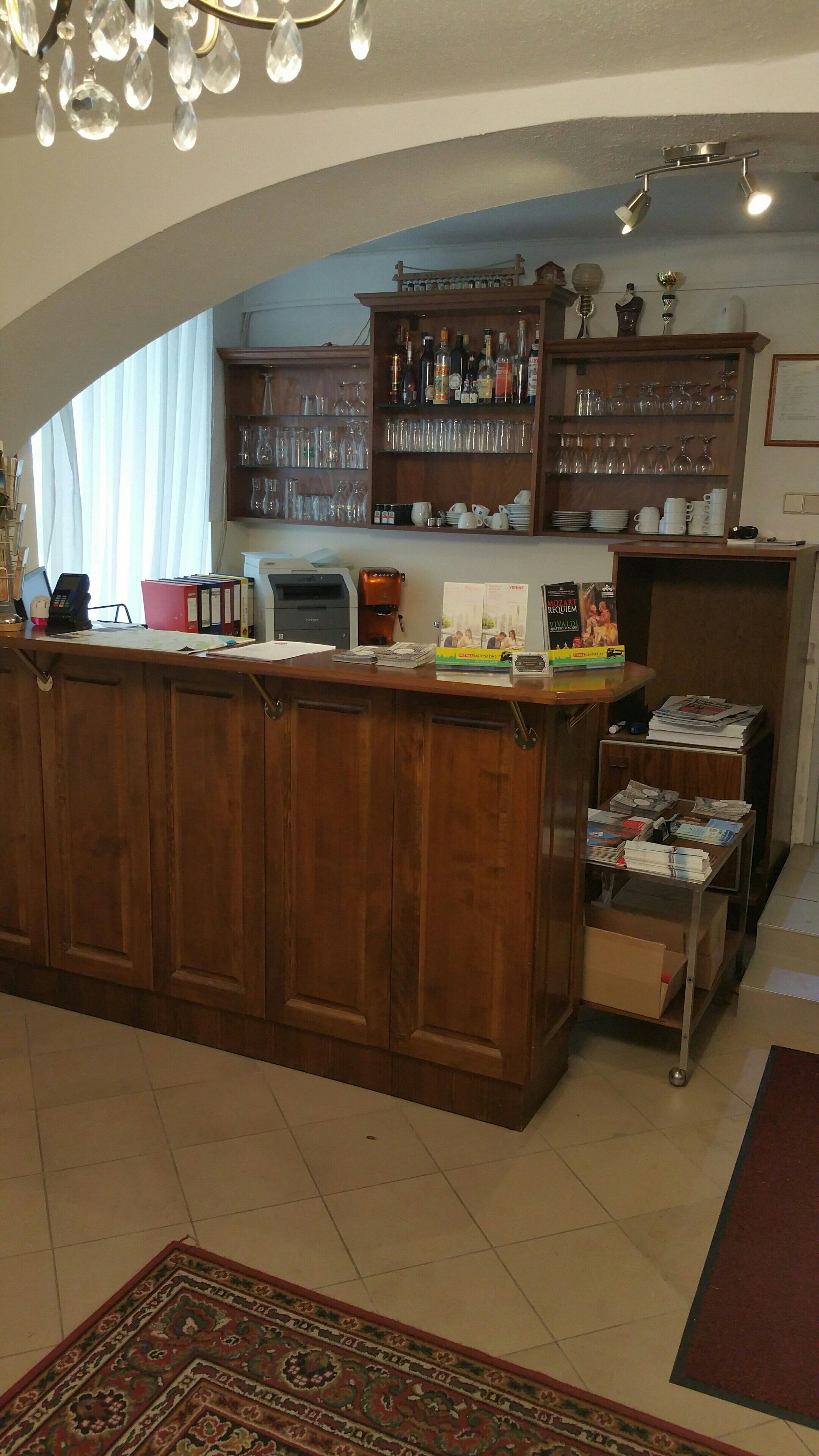 Een bar met houten kasten, een aanrecht met diverse spullen, en een boekenkast vol met glaswerk en flessen.