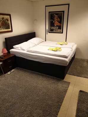 A neatly made bed with white linens and a folded towel, a bedside lamp, and a framed picture on the wall. - Appartementhotel Marien-Hof (Vienna)