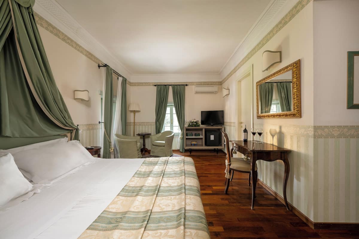 Une chambre d’hôtel avec un grand lit, un bureau, une chaise, une télévision et un miroir.