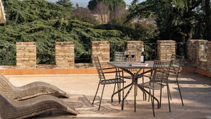 An outdoor patio with a table and chairs, surrounded by brick walls and greenery. - RELAIS PARCO DEI CAVALIERI ASSISI (Assisi)