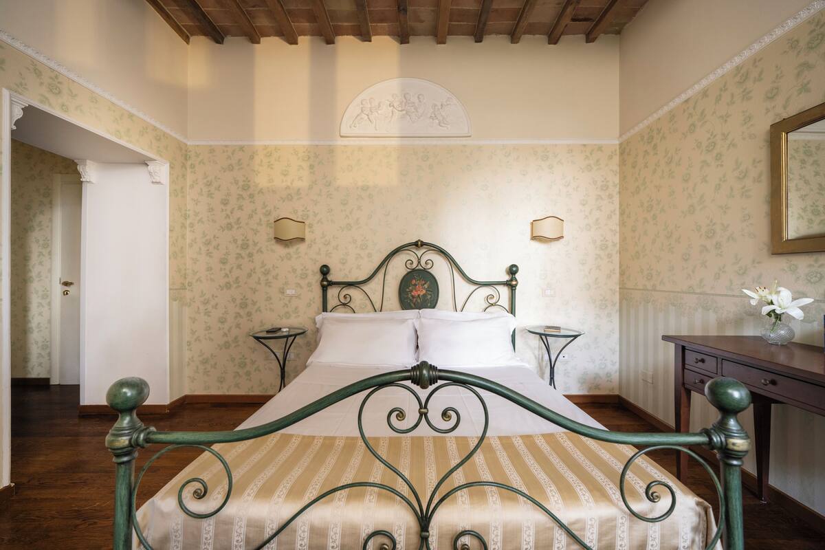 Une chambre à coucher comprenant un lit, une table de chevet, une commode et un miroir.