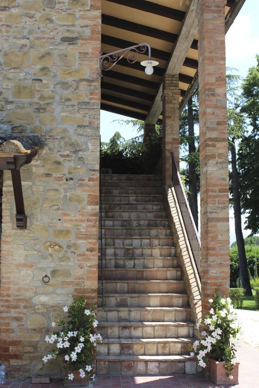 A stone staircase with a metal railing, leading to an upper level.