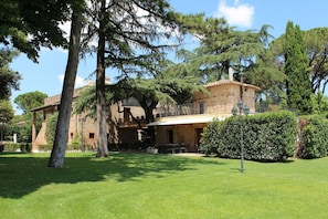 Una villa rústica con fachada de piedra, un balcón y un jardín bien cuidado.
