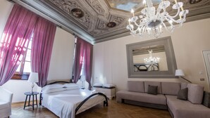 A hotel room with a bed, a sofa, a chandelier, and a large mirror. - N4U Guest House (Florence)