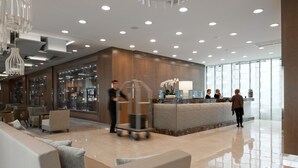 Een moderne lobby met een receptiebalie, een zithoek en een groot raam voor natuurlijk licht.