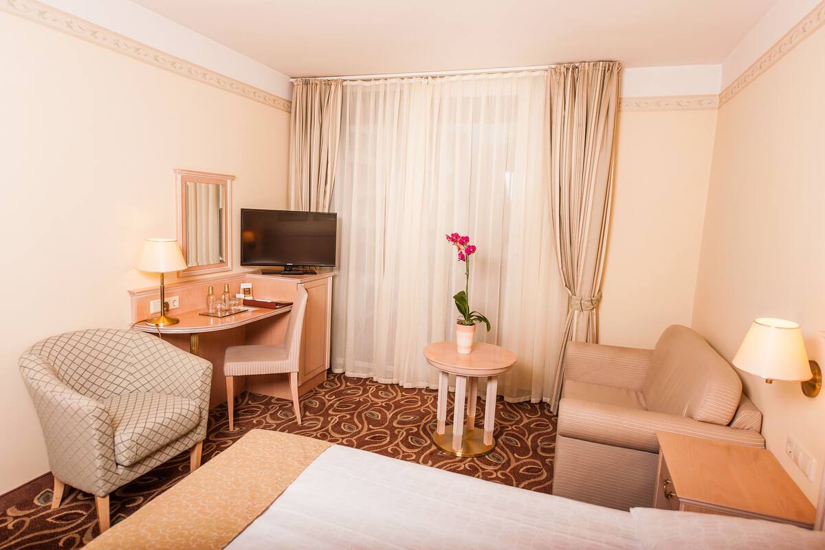 Une chambre d’hôtel comprenant un lit, un bureau, une chaise, une télévision et une petite table avec une lampe.