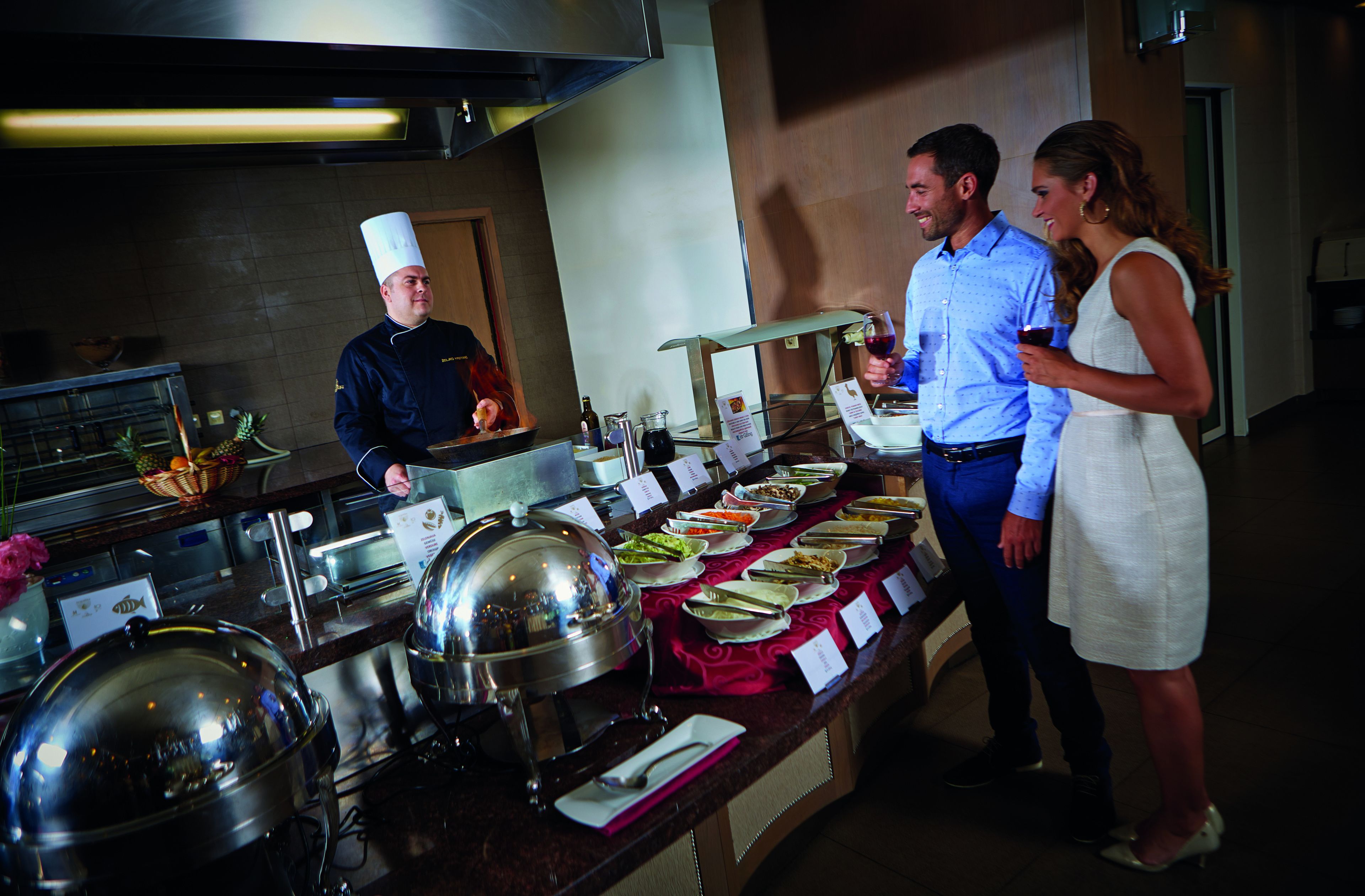 A buffet setup with various dishes and a chef in uniform.