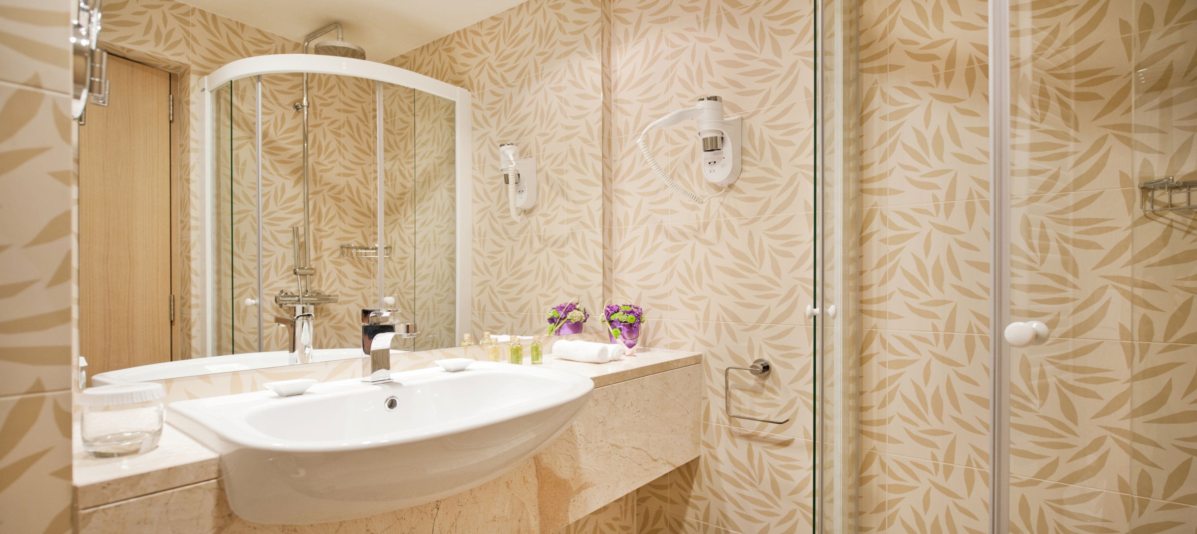 A bathroom with a large sink, mirror, and shower.