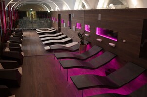 Un spa moderno con sillones reclinables curvos e iluminación ambiental rosa.