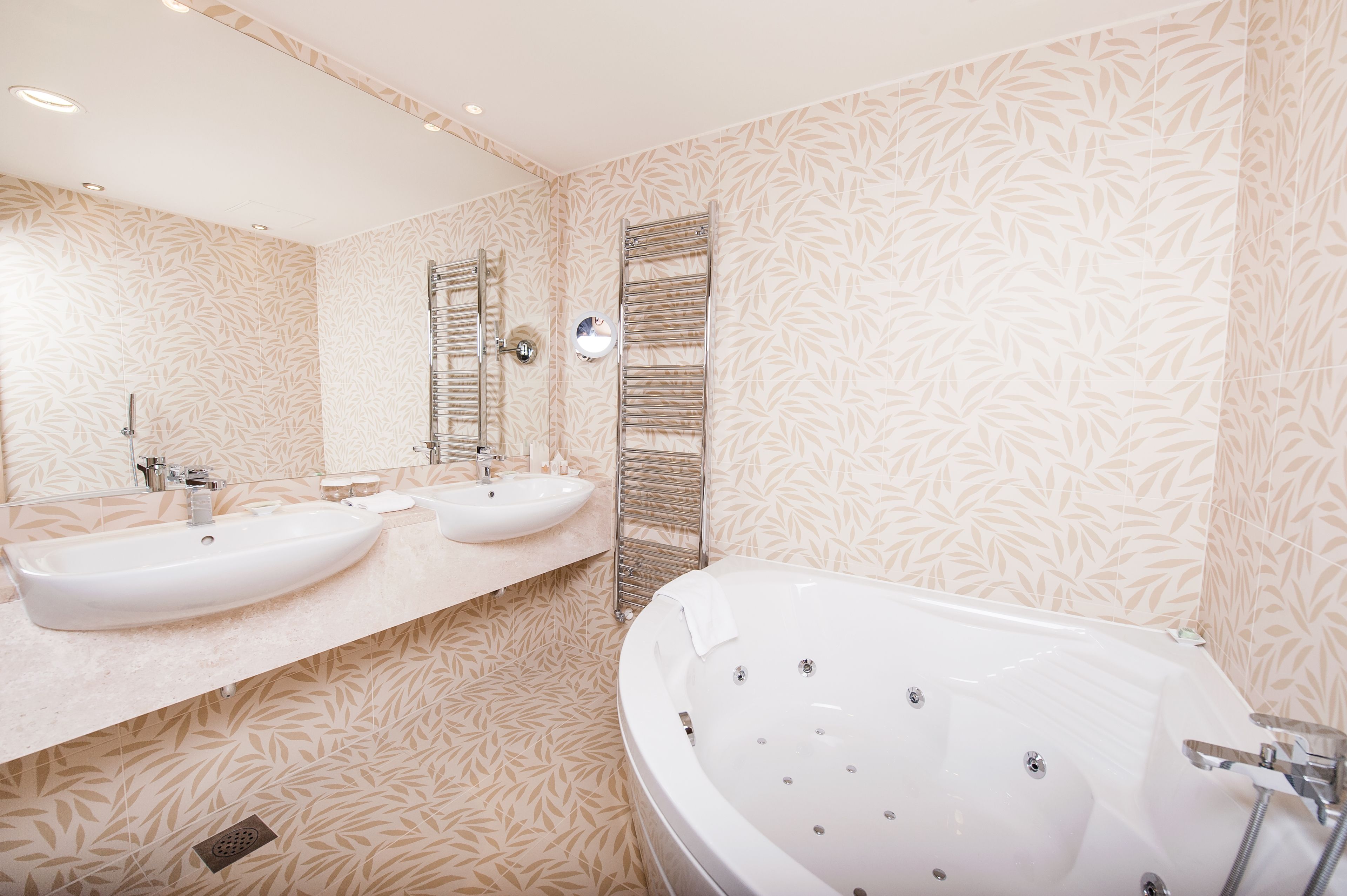 A modern bathroom with two sinks, a large bathtub, and a mirror.