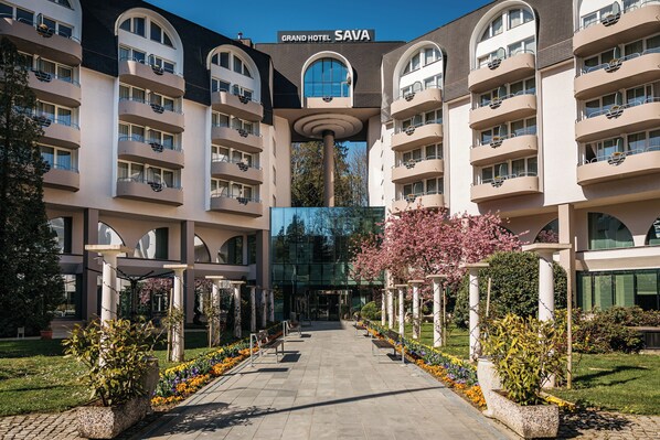 A multi-story hotel with a central atrium, balconies on each floor, and a garden with benches.