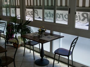 A dining area with a table and chairs, a potted plant, and a view through the window. - Locanda la Rotonda (Montale)