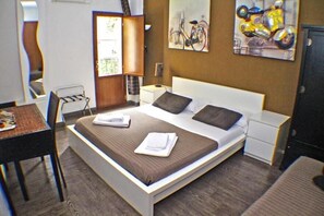 Una habitación de hotel moderna con una cama grande, mesitas de noche, una silla y obras de arte en las paredes.
