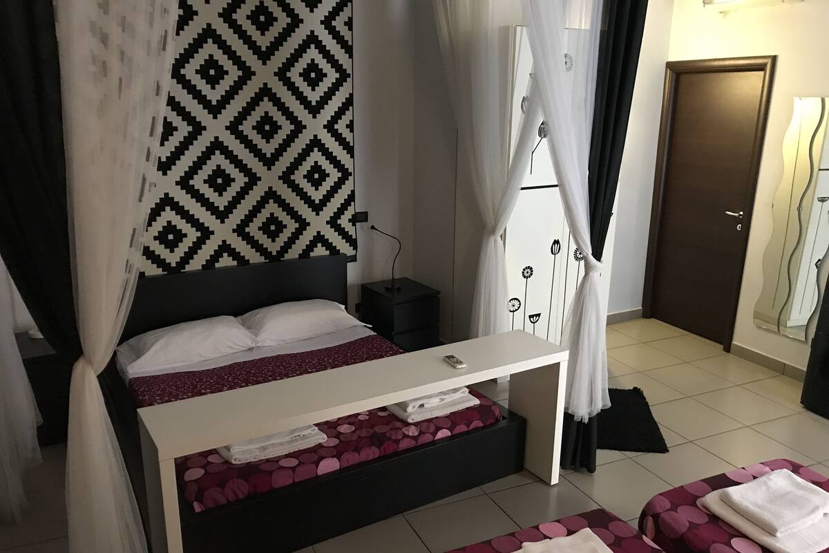A bedroom with a bed, bedside table, and two bedside chairs.