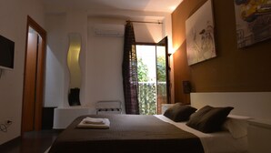 Habitación de hotel con cama, ventana con cortinas, televisor montado y un cuadro en la pared.