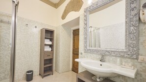 A bathroom with a large mirror, a sink, a shower, and a towel rack. - Residenza Maglioni al Battistero (Florence)