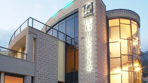 A hotel with a modern brick facade, large glass windows, and a well-lit entrance. - Hotel Le Ginestre (Roccacasale)