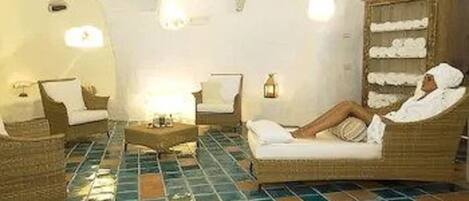 A room with a tiled floor, two wicker chairs, a sofa, and a wooden cabinet.