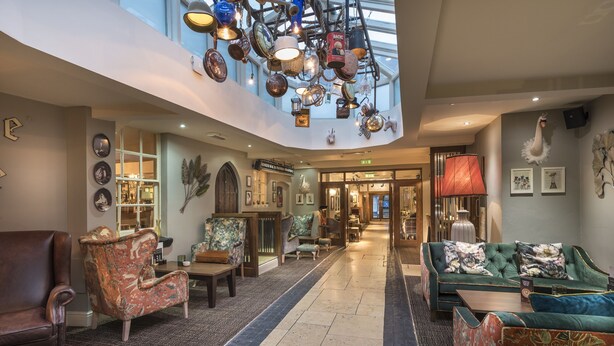 A spacious lobby with a high ceiling, ornate chandeliers, and a variety of seating options including plush sofas and armchairs.