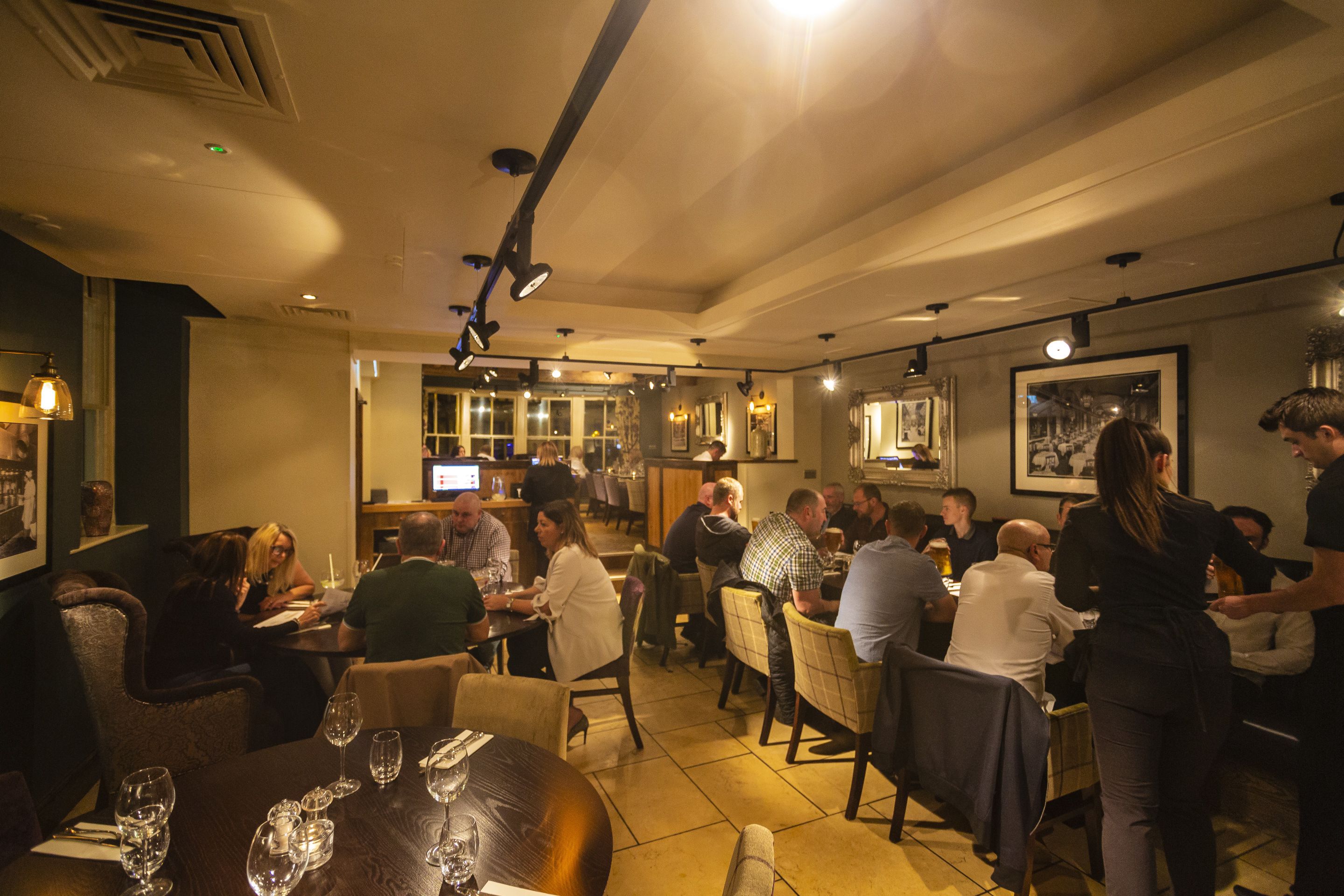 En restaurant med flere borde, stole, et barområde og en disk.