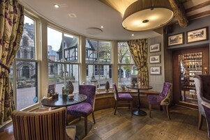 Una habitación acogedora con ventanas amplias, suelo de madera y sillones tapizados en color morado.