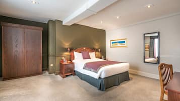 A bedroom with a large bed, a wooden wardrobe, a nightstand, and a mirror on the wall.