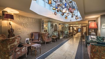 A lobby with a high ceiling, patterned chairs, a central table, and a wall with a sign.