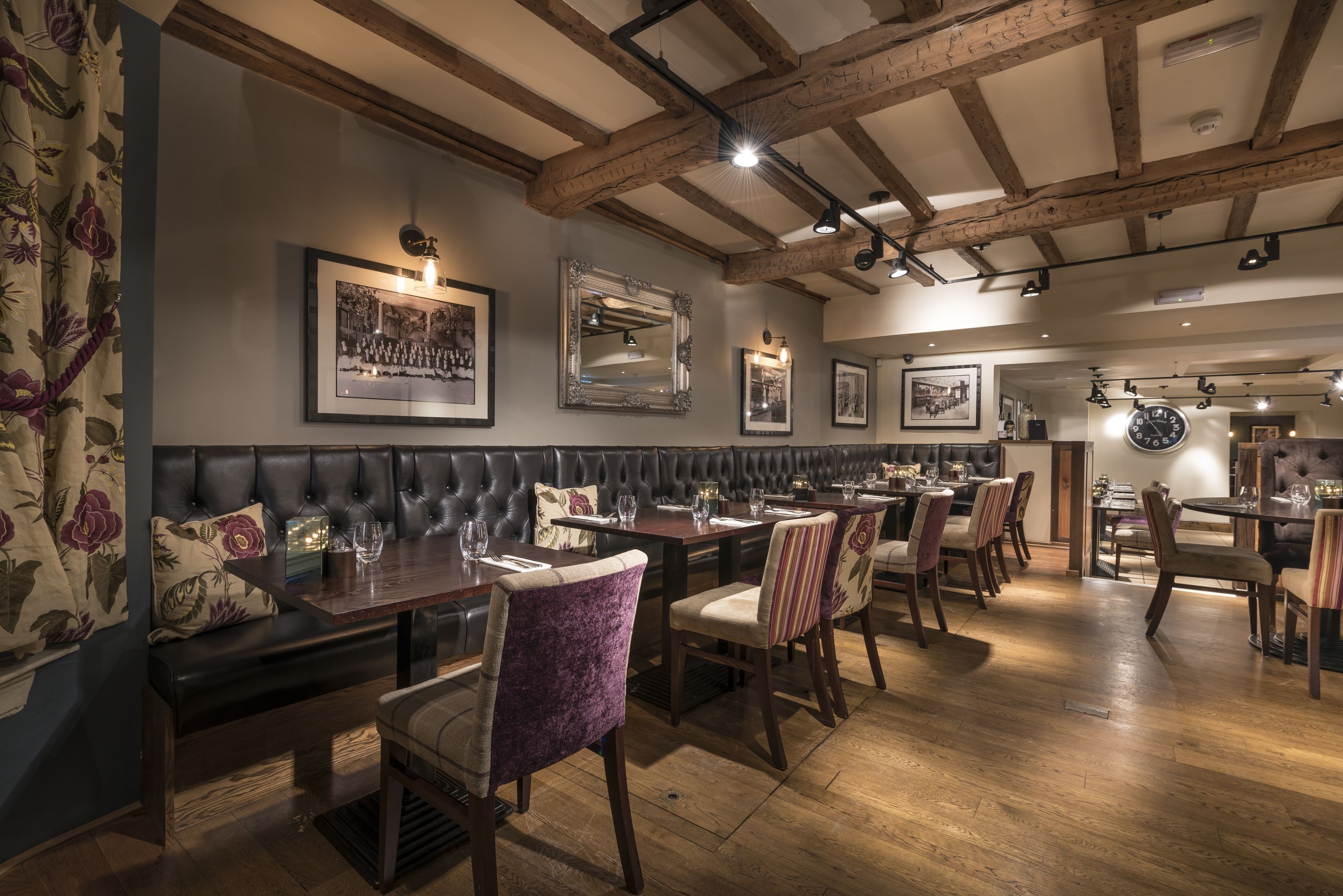 A restaurant with wooden beams, cushioned seating, and framed pictures on the walls.