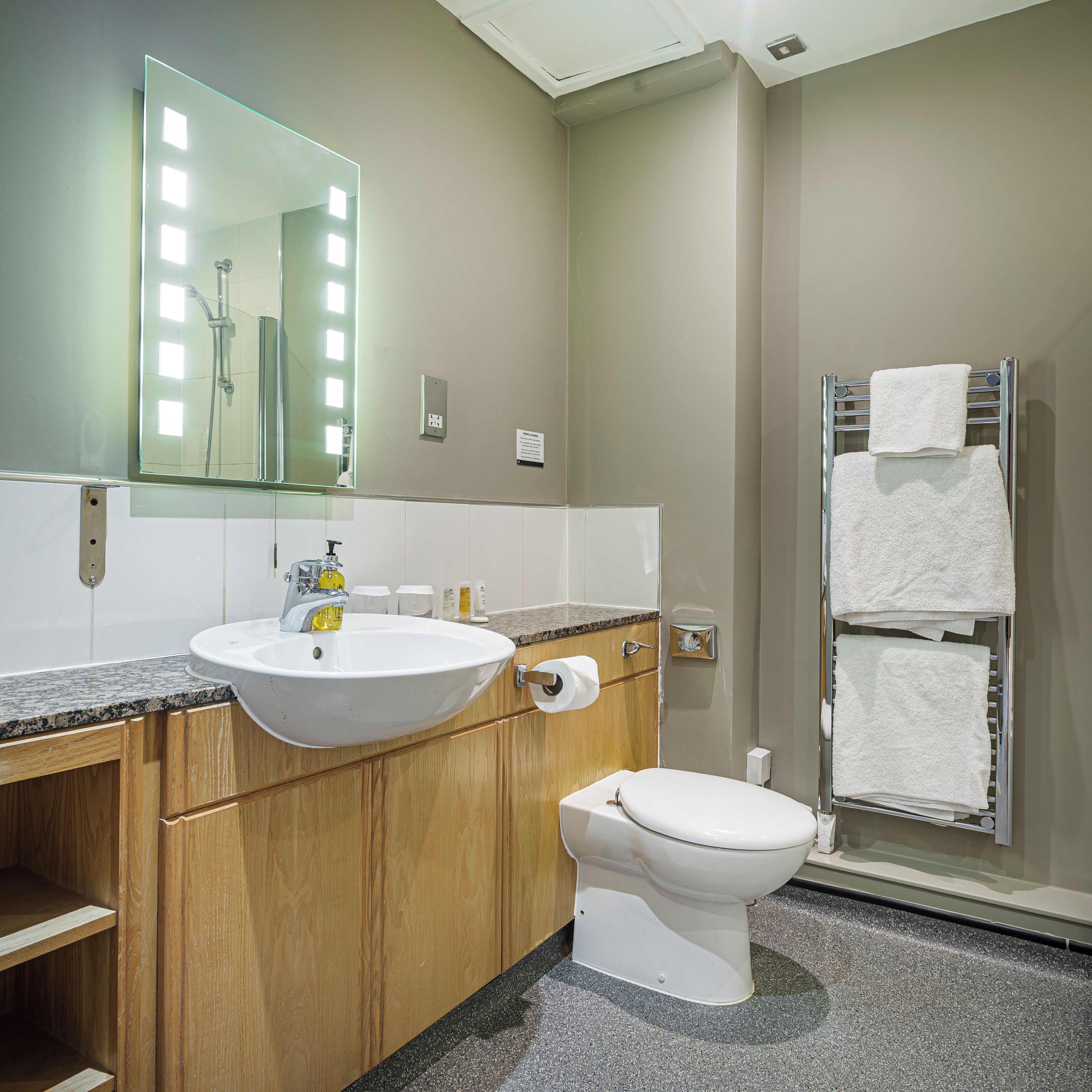 A bathroom with a sink, mirror, toilet, and towel rack.