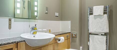 A bathroom with a sink, mirror, toilet, and towel rack.