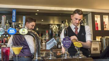 Zona de bar con grifos de cerveza identificados como 'Bud Light', 'Leffe', 'Wainwright' y 'Tribute'.