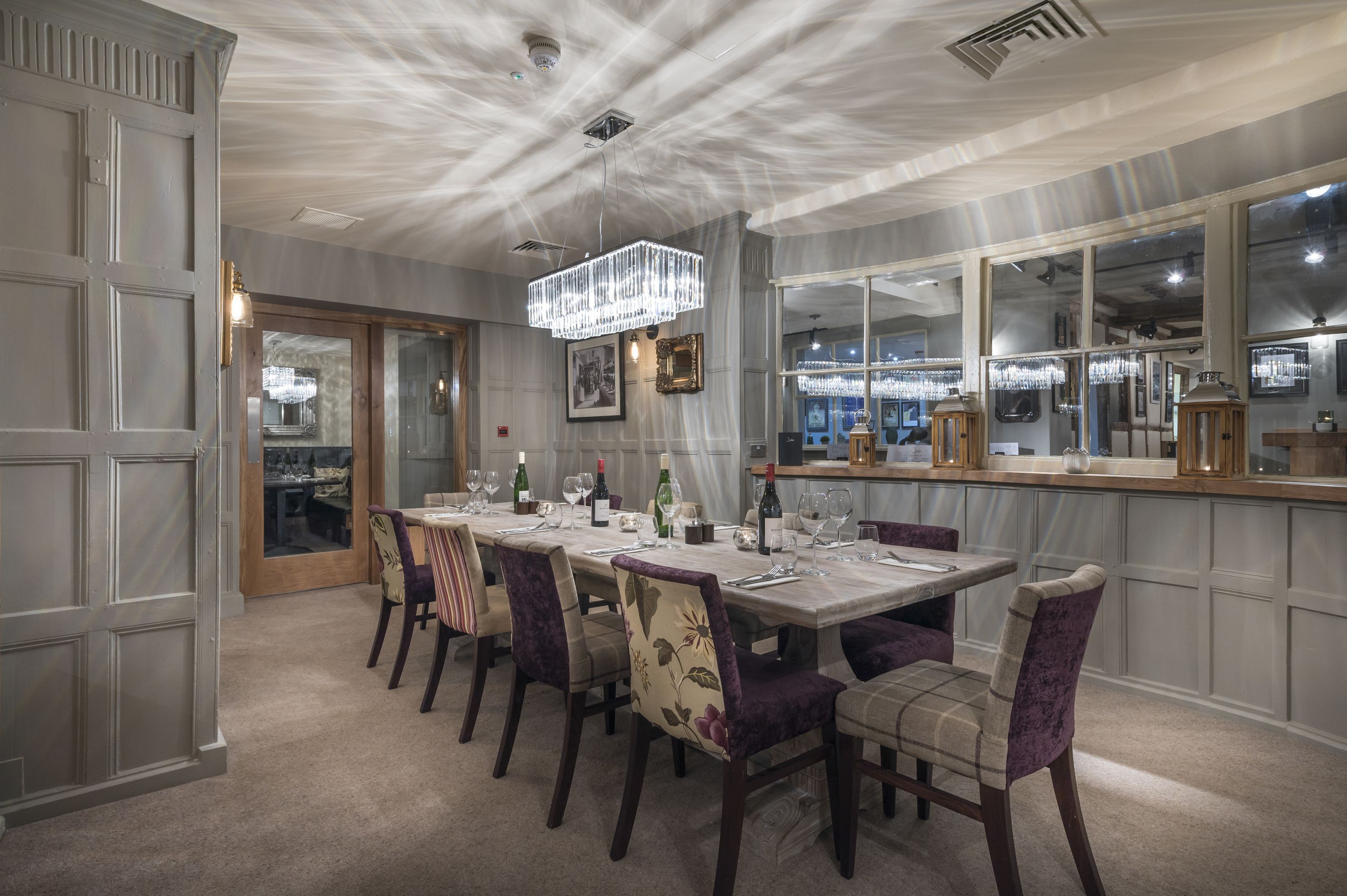 A dining area with a long table set for six, surrounded by chairs with floral upholstery.