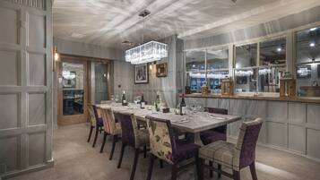 A dining area with a long table set for six, surrounded by chairs with floral upholstery.