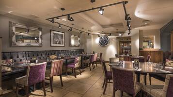 Un restaurante con una larga mesa de comedor, cabinas acolchadas y sillas a rayas.