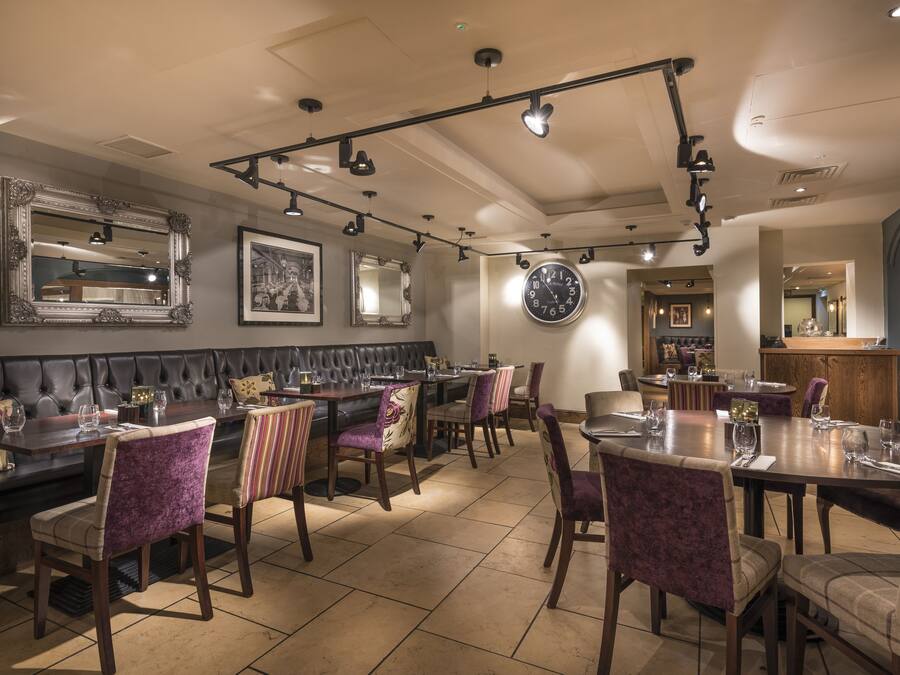 Un restaurante con una larga mesa de comedor, cabinas acolchadas y sillas a rayas.