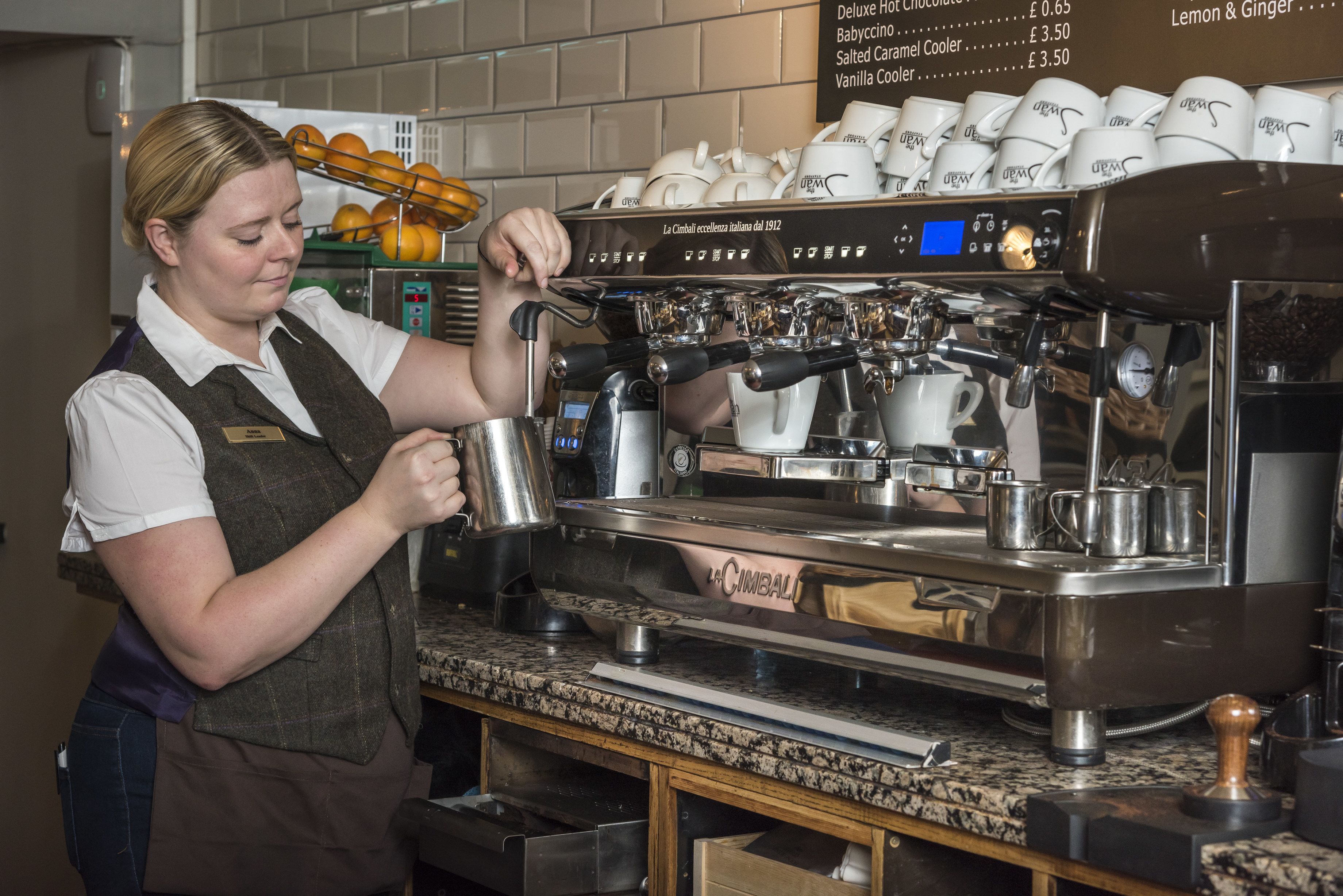 En barista laver en drik ved en kaffemaskine.