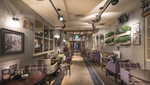 A hotel corridor with multiple seating areas, framed pictures on the walls, and a central walkway.