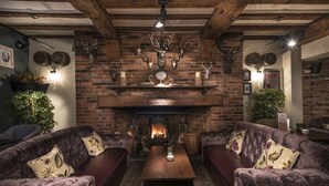 A cozy room with a brick fireplace, leather sofas, and antler decorations.
